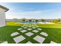 Lush backyard features a sparkling pool, artificial turf, and inviting lounge chairs for sun-soaked relaxation at 10918 W Dove Roost Rd, Queen Creek, AZ 85144