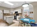 Bright kitchen featuring white cabinetry, an island, stone countertops, and an open view to the living area at 11775 E Becker Ln, Scottsdale, AZ 85259