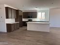 Open kitchen with white countertops, tile backsplash, and dark wood cabinetry with island at 18383 W Monte Lindo Ln, Surprise, AZ 85387