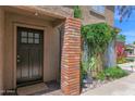 Inviting front entryway with a brick pillar, lush greenery, and a stylish black door at 2941 E Nisbet Ct, Phoenix, AZ 85032
