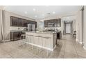 Modern kitchen with dark cabinets, stainless steel appliances, granite countertops, and a large center island at 37645 W Santa Clara Ave, Maricopa, AZ 85138