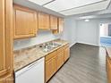 Well-lit kitchen with stainless steel sink, ample wood cabinets, laminate countertops, and modern flooring at 3810 N Maryvale Pkwy # 1070, Phoenix, AZ 85031