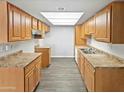 Well-lit kitchen with stainless steel sink, ample wood cabinets, laminate countertops, and modern flooring at 3810 N Maryvale Pkwy # 1070, Phoenix, AZ 85031