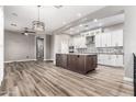 Open-concept living room and kitchen features a large kitchen island with grey granite countertop, white cabinets and stainless appliances at 42424 N Gavilan Peak Pkwy # 24206, Anthem, AZ 85086