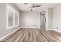 Neutral living room with gray walls, ceiling fan, wood-look tile floors, shuttered windows, and views of the hallway and doorway at 42424 N Gavilan Peak Pkwy # 24206, Anthem, AZ 85086