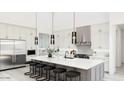 Modern kitchen with stainless steel appliances, white cabinets, an island, and stylish pendant lighting at 5919 E Corrine Dr, Scottsdale, AZ 85254