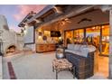Cozy outdoor living space with built-in fireplace, bar area, and comfortable wicker furniture at 8514 E Country Club Trl, Scottsdale, AZ 85255