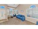 Bright living room with a vaulted ceiling, tiled entry, and plush blue furnishings at 9026 W Cambridge Ave, Phoenix, AZ 85037