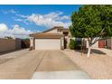 Traditional-style single-story home features a concrete driveway, tan stucco, and a two-car garage with direct entry at 1043 N 90Th Cir, Mesa, AZ 85207