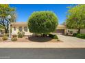 A cozy single-story home with lush landscaping, a tiled roof, and a two-car garage at 13134 W Los Bancos Ct, Sun City West, AZ 85375