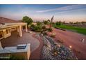 Picturesque backyard with a beautiful water feature, putting green view and a covered patio with an outdoor kitchen at 22208 N San Ramon Dr, Sun City West, AZ 85375