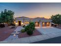 Charming desert home with a tiled roof, three-car garage, and landscaped yard at dusk at 22208 N San Ramon Dr, Sun City West, AZ 85375