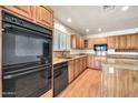 Well-lit kitchen featuring granite countertops, light wood cabinets, and modern black appliances at 5126 W Las Palmaritas Dr, Glendale, AZ 85302