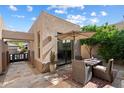 A cozy outdoor patio setup features a dining table under an umbrella, surrounded by lush greenery at 6579 E Shooting Star Way, Scottsdale, AZ 85266
