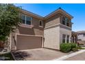 View of the two-car garage of this house, complete with a brick driveway and lush front yard greenery at 9733 E Axle Ave, Mesa, AZ 85212