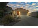 Front exterior featuring an arched entrance, a two-car garage, and desert landscaping under a beautiful sunset sky at 14916 W Georgia Dr, Surprise, AZ 85379