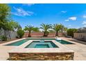 Backyard oasis featuring a sparkling pool, spa, and lush landscaping, perfect for relaxing and entertaining at 14916 W Georgia Dr, Surprise, AZ 85379