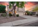 Charming two-story home featuring a well-manicured lawn, mature trees, and a spacious driveway leading to the garage at 16153 W Lisbon Ln, Surprise, AZ 85379