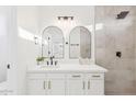 Elegant bathroom features a double vanity with modern fixtures, arched mirrors, and a walk-in shower with tile surround at 7838 N 110 Ln, Glendale, AZ 85307