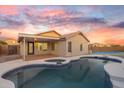 Inviting backyard with a refreshing pool, covered patio, and a tennis court under a vibrant sunset at 7838 N 110 Ln, Glendale, AZ 85307