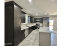 Well-lit kitchen with an island, modern appliances, sleek cabinetry, and tile flooring throughout the house at 11216 W Apache St, Avondale, AZ 85323