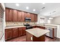 Kitchen with stainless appliances, central island, and wood cabinets with stone countertops at 12838 W Desert Mirage Dr, Peoria, AZ 85383