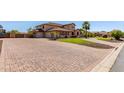 Expansive brick driveway leading to a meticulously landscaped home, highlighting the property's curb appeal at 14107 W Christy Dr, Surprise, AZ 85379