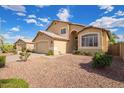 Well-maintained tan home featuring a two-car garage, desert landscaping, and mature greenery at 2327 E Edna Ave, Phoenix, AZ 85022