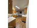 Functional kitchen with wooden cabinets, laminate countertops, and wood-style flooring at 3434 W Augusta Ave, Phoenix, AZ 85051