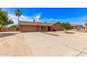 Well-maintained single-story brick home with a two-car garage, long driveway, and desert landscaping at 8913 W Country Club Trl, Peoria, AZ 85383