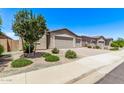 Tan home featuring a two-car garage, beautiful landscaping, and a brick driveway at 1268 E Jahns Dr, Casa Grande, AZ 85122