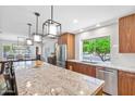 Kitchen island featuring granite countertops, modern pendant lighting, and stainless steel appliances at 17890 N 99Th Dr, Sun City, AZ 85373
