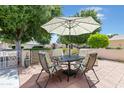 Outdoor patio seating area with a table, chairs, decorative umbrella, and a brick-paved surface at 17890 N 99Th Dr, Sun City, AZ 85373
