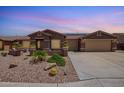Charming single-story home with a three-car garage, desert landscaping, and front yard patio at 20427 N 88Th Dr, Peoria, AZ 85382