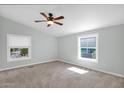Neutral bedroom featuring two sunny windows, a ceiling fan, and plush carpeting at 2400 E Baseline Ave # 228, Apache Junction, AZ 85119