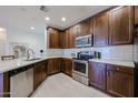 Modern kitchen with stainless steel appliances, tiled backsplash, and dark cabinets at 2511 W Queen Creek Rd # 337, Chandler, AZ 85248