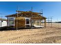 Framed house showcasing the construction process with the bare framework, window openings, and roof supports against a blue sky at 46887 W Old Timer Rd, Maricopa, AZ 85139