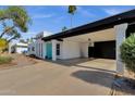 View of the black carport of a white home with blue front door and desert landscaping at 6401 E Voltaire Ave, Scottsdale, AZ 85254