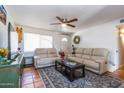 Cozy living room featuring neutral couches, a ceiling fan, and a stylish rug with colorful flowers adding a touch of charm at 6501 W Columbus Ave, Phoenix, AZ 85033
