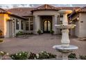 Elegant home with arched entryway, mature landscaping, and statement fountain feature at 7327 E La Junta Rd, Scottsdale, AZ 85255
