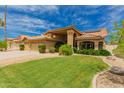 Well-maintained single Gathering home featuring lush green lawn and desert landscaping, terra cotta tile roof, and 3-car garage at 1590 W Desert Broom Dr, Chandler, AZ 85248