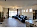 Spacious living room featuring tile floors, ceiling fan and sliding glass door to backyard at 15951 W Yavapai St, Goodyear, AZ 85338