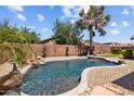 Backyard pool with rock waterfall feature, surrounding gravel, and privacy wall at 16648 W Adams St, Goodyear, AZ 85338