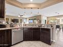 Modern kitchen area with granite countertops, stainless steel dishwasher, dark wood cabinets, and pendant lighting at 25540 N 103Rd Dr, Peoria, AZ 85383