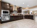 A spacious kitchen featuring dark cabinets, stainless steel appliances, and granite countertops, perfect for culinary enthusiasts at 25540 N 103Rd Dr, Peoria, AZ 85383