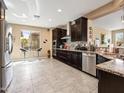 Spacious kitchen showcasing dark wood cabinets, granite countertops, stainless steel appliances, and a breakfast bar at 25540 N 103Rd Dr, Peoria, AZ 85383