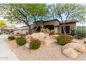 Single story home featuring desert landscaping, including rocks, red flowers and shade trees at 25845 N 44Th Ave, Phoenix, AZ 85083