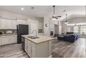 Open-concept kitchen and living room featuring a stone fireplace, ceiling fans, and wood floors at 3580 E Kesler Ln, Gilbert, AZ 85295