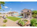 Expansive backyard featuring a pool, turf area, pergola, and lush landscaping at 43612 W Chambers Ct, Maricopa, AZ 85138