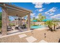 Covered patio with comfortable seating area overlooking the pool and backyard at 43612 W Chambers Ct, Maricopa, AZ 85138